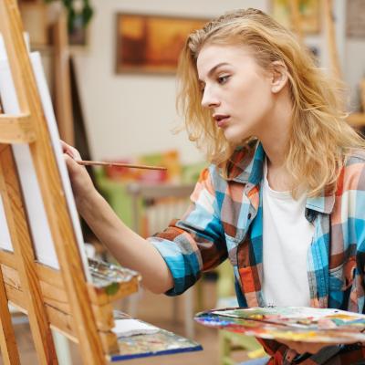female artist at easel with paints